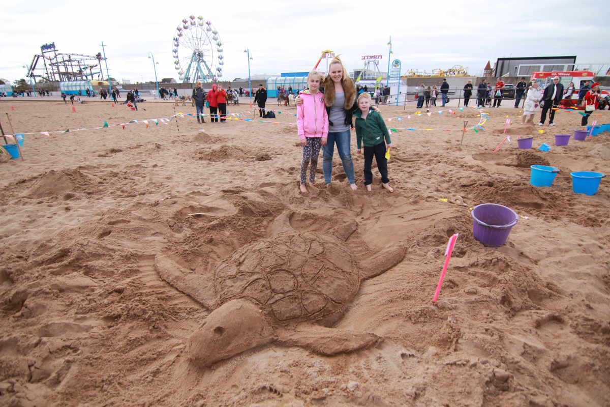 Sand sculpture competition winner with their turtle