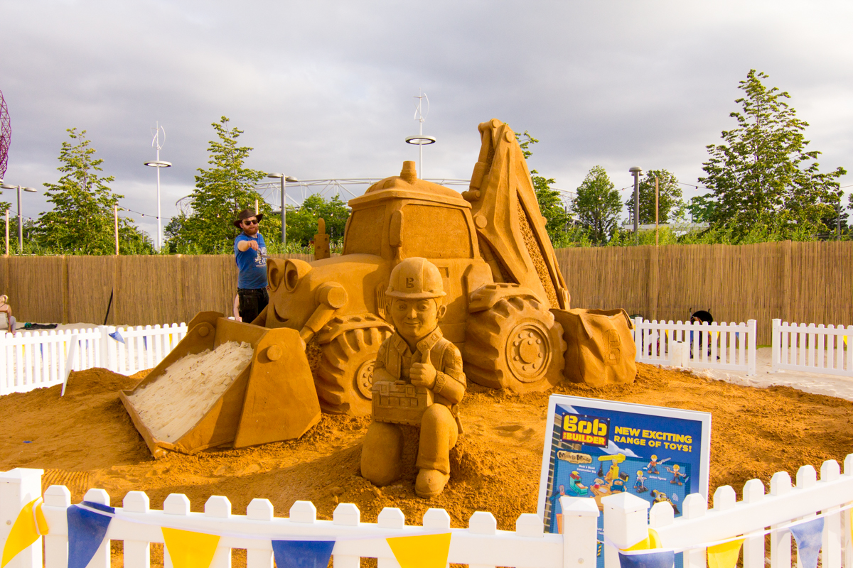 UK sand sculptor Jamie Wardley poses with the giant Bob The Builder sand sculpture at an urban beach event London